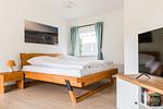 Helles Schlafzimmer mit Holzbett und Fernseher - Haus Windflüchter - Top-Hundeurlaub