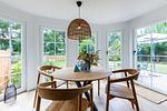 Essbereich mit rundem Holztisch und vier Stühlen, Blumenstrauß in der Mitte, große Fenster mit Blick in den Garten. - Boddenblick 1 - Top-Hundeurlaub