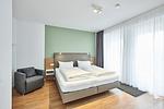 Schlafzimmer mit Doppelbett, Sessel und Zugang zum Balkon - Deichhäuser Anna Küste 4-24 - Top-Hundeurlaub