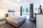 Schlafzimmer mit Boxspringbett und TV - Aparthotel Ostseeallee 5-42 - Top-Hundeurlaub
