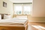 Helles Schlafzimmer mit Doppelbett und Fenstern - Schwinkelsmoor - Top-Hundeurlaub