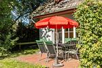 Terrasse mit Tisch und rotem Sonnenschirm - Schwinkelsmoor - Top-Hundeurlaub