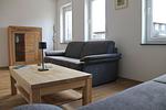 Im heimeligen Wohnzimmer stehen 2 Schlafsofas. Für Unterhaltung sorgt der große Fernseher mit Magenta TV - Ferienhaus Familien-Idyll Bibertalblick - Top-Hundeurlaub