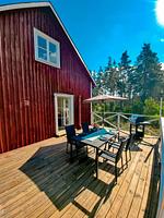 Holzterrasse der Villa Clara am roten Schwedenhaus mit Sitzplatz und Blick ins grüne Naturgrundstück in Småland - Villa Clara - Top-Hundeurlaub