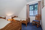erstes Schlafzimmer mit Einzelbetten und Stuhl - Wohnung 08-5 - Top-Hundeurlaub