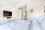 Schlafzimmer "1" mit Boxspringbett, TV und Blick zum Flur - Aparthotel Ostseeallee 5-46 - Top-Hundeurlaub