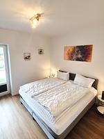 Schlafzimmer mit Doppelbett und Kunstwerk - Ferienhaus Kuestenliebe - Top-Hundeurlaub