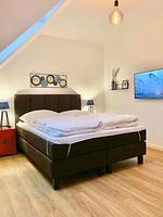 Schlafzimmer mit Doppelbett, Nachttischen und Fernseher. - Ferienhaus Lea - Top-Hundeurlaub