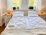 Doppelbett mit weißen Bettdecken und Nachttischen. - Ferienhaus Luke - Top-Hundeurlaub