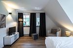 Helles Schlafzimmer mit Fernseher und Sessel - Sanddornhus - Top-Hundeurlaub