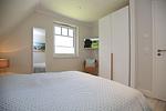 1. Schlafzimmer mit Doppelbett, TV  und Kleiderschrank - Reethaus 18b - Huus Berti - Top-Hundeurlaub