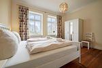 Schlafzimmer zur Gartenseite mit großem Doppelbett und Kleiderschrank - Ferienwohnung Gut Hardesby - Top-Hundeurlaub