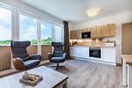 Wohn-/Essbereich mit Couchtisch, Sessel und Küchenzeile - Aparthotel Ostseeallee 3-25 - Top-Hundeurlaub