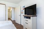 Schlafzimmer mit Boxspringbett und TV - Aparthotel Ostseeallee 3-25 - Top-Hundeurlaub