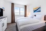 Schlafzimmer mit Doppelbett, Fenster und TV - Aparthotel Ostseeallee 3-28 - Top-Hundeurlaub