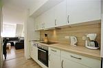 Küchenzeile mit Backofen und Spülmaschine  und Blick zum Wohnzimmer - Wohnung 05-7 - Top-Hundeurlaub