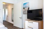 Schlafzimmer mit TV und Zugang zum Flur - Aparthotel Ostseeallee 2-08 - Top-Hundeurlaub