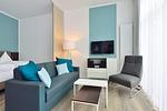 Wohn/ Essbereich mit Couch, Tisch und Fernseher - Aparthotel Anna Düne 0-05 - Top-Hundeurlaub