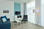 Wohn/ Essbereich mit Couch, Sessel und Fernseher - Aparthotel Anna Düne 0-06 - Top-Hundeurlaub