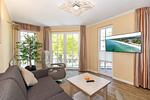 Wohn-Essbereich mit Couch und Flatscreen-TV - Apartmenthaus Atlantik 102 - Top-Hundeurlaub