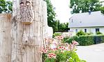 Holzpfosten mit Blumen und Gebäude im Hintergrund - Sonnenblumenhaus 01 - Top-Hundeurlaub