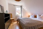 Schlafzimmer mit großem Bett und Stuhl - Haus Ostseenixe 03 - Top-Hundeurlaub